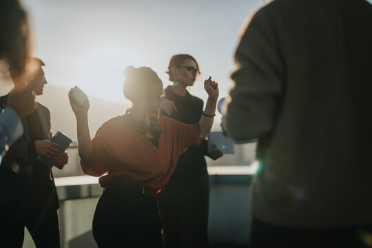 A diverse group of business colleagues celebrates together on a high tower balcony during sunset, enjoying a moment of joy and camaraderie. Perfect image for teamwork and success concepts.