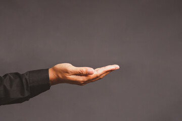 Close-up of an open hand in a black sleeve extended against a plain dark background.