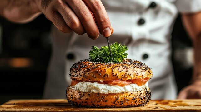 front view close up of a chef preparing a bagel with smoked salmon, cream cheese and caviar, we see him placing a very small parsely leaf with his chef - Powered by Adobe