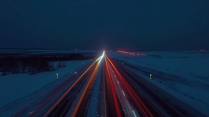 Obraz premium The quietness of a country road at night is interrupted by the bright light trails of passing vehicles creating a gorgeous contrast.
