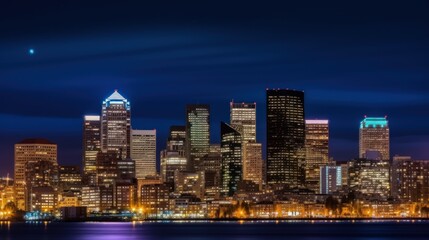 Fototapeta premium Nighttime city skyline illuminated with lights against a dark blue sky.
