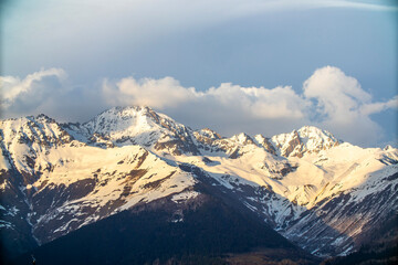 A snowy mountain range appears majestic under a cloudy sky