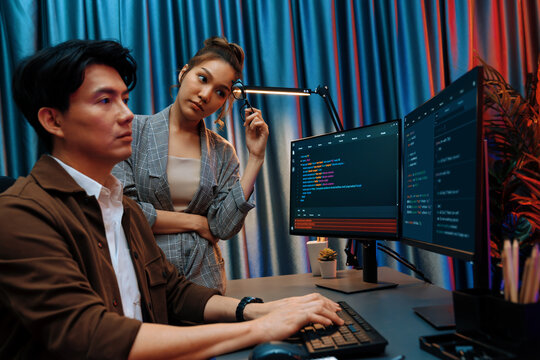 IT developers discussing with point to intelligent website development coder system running data online two screens information technology at neon light room at modern office. Infobahn.