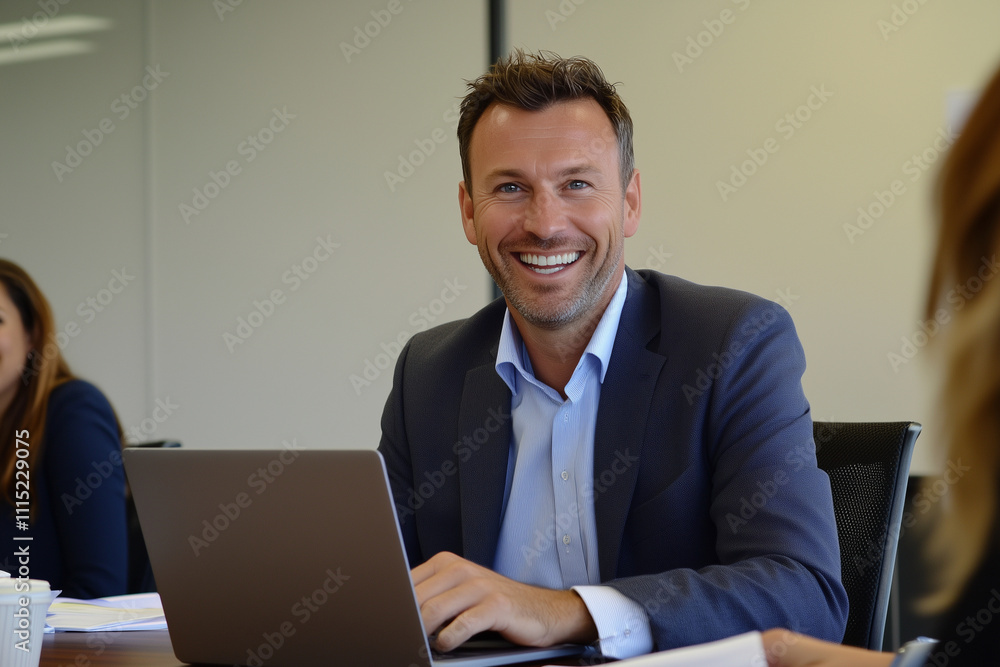Poster man in a suit is smiling and sitting at a desk with a laptop. he is happy and content while working 
