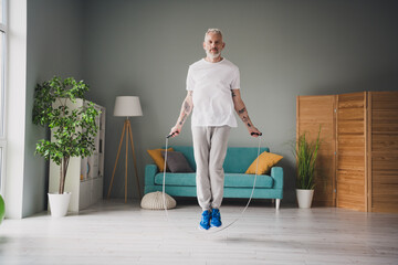 Active senior man jumping rope indoors for fitness and bodycare workout