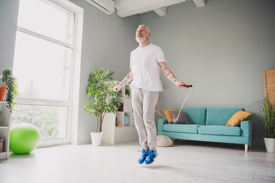Elderly man enjoying an energetic jump rope workout in a bright, modern living room setting