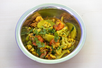 Delicious shrimp curry with cauliflower and potatoes, served in a steel bowl.