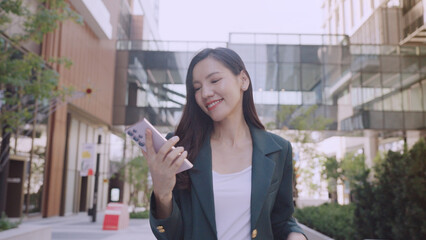 Fototapeta premium confident woman smiles while using her smartphone outdoors in modern urban setting