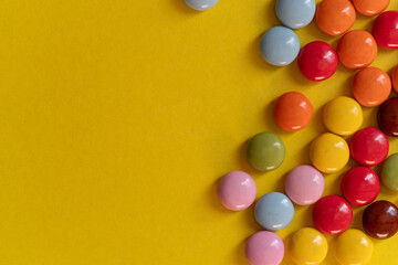 Obraz premium 黄色背景に並ぶカラフルなチョコレート