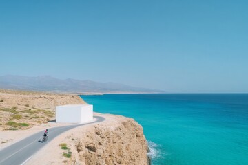 Obraz premium Cyclist Enjoying Serene Coastal Ride on Winding Cliffside Road