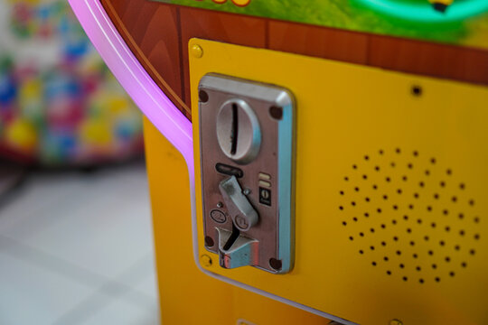 A detailed view of an arcade game's control panel, showcasing its vibrant yellow color and various interactive elements. Close-up of a Yellow Arcade Game Machine's Coin Slot.