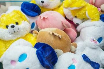 Close-up view of a pile of various colorful stuffed animals. Yellow, pink, white, and brown plush toys are seen. A Pile of Plush Toys: Yellow, Pink, White, and Brown Stuffed Animals.