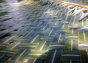 A close-up of a woven mat made from coconut leaves highlights its intricate pattern, natural green-brown hues, and craftsmanship, symbolizing traditional, eco-friendly, and cultural heritage.