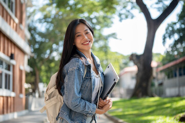 A cheerful Asian female college student on her way to class, smiling at the camera.