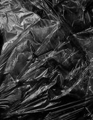 Close-up of a black crumpled plastic surface with circular bumps and dimples, glossy texture, abstract industrial feel, high contrast lighting, wrinkled and irregular pattern.