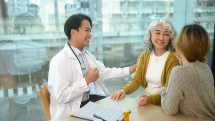 Fototapeta premium Caring doctor talking to senior woman during consultation at hospital. Healthcare and medical concept