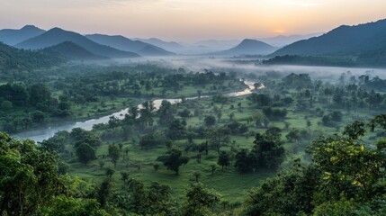 Misty Morning Landscape with River Winding Through Lush Green Valley and Distant Hills