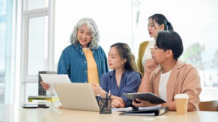 Fototapeta premium An Asian business startup team brainstorming and discussing a project in a modern office.