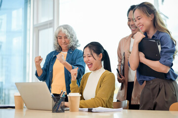 A group of cheerful, diverse Asian businesspeople celebrate their project success in the office.