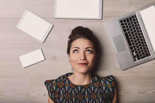 Young woman lying on floor thinking about technology