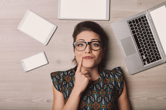 Young woman lying on floor thinking about modern technology