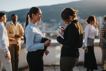 A diverse group of business colleagues brainstorms on a high tower balcony during sunset. The...