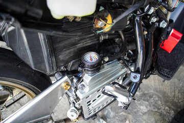 Fototapeta premium Detailed close-up of a motorcycle's modified engine bay, showcasing a custom gauge and other mechanical components. Detailed View of Coolant Temperature Gauge and Components