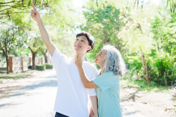 A happy senior mother embraces her smiling adult son in a lush green park. Surrounded by nature, their affectionate hug symbolizes love, peace, vitality, and renewal under the serene greenery