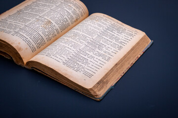 Obraz premium Close-up of an open antique dictionary against dark background. Selective focus