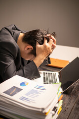 A man works overtime at his desk in the office of the office to clear documents to send to the customer. During work, he is stressed from work and happy after finishing the work for the customer.