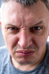 portrait of an aggressive angry man with a face distorted with hatred and malice