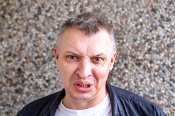 portrait of an aggressive angry man with a face distorted with hatred and malice