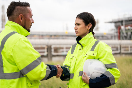 Engineer worker hand shaking to colleagues team for success work at construction site of petroleumchemical industry or refinery oil plant factory