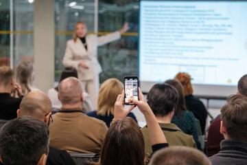 Audience in business presentation capturing information with smartphone highlighting modern interaction