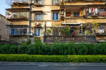 a worn, aging, decaying multi-story apartment building with cluttered balconies and hanging laundry...