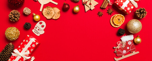 Fototapeta premium Top view of Christmas decorations on red background. New Year holiday concept with copy space