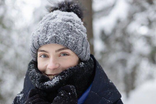Woman covering face with wool scarf in winter forest on snowy day