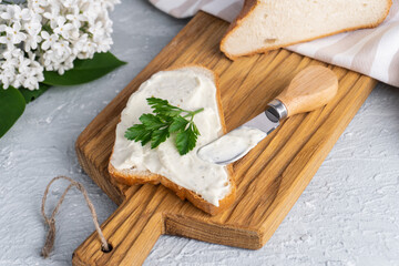 Cream cheese with herbs and seasoning on slice of fresh crunchy rye bread with cheese knife nearby