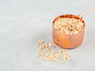 Rolled oats in measuring cup on wooden board