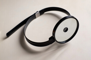 A reflector for an otolaryngologist is on a white table. Horizontal shot.
