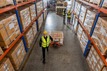 Man worker wear safety uniform push load cart product to shelf in warehouse store. Company employees arrange products. Warehouse industrial stock storage.