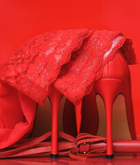 red high heels and whip on red background