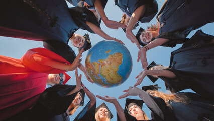 Group of diverse graduates forming a circle around a globe, symbolizing their readiness to embrace...