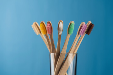 Set of colorful bamboo toothbrushes in glass on blue background, closeup. Zero waste, plastic free, eco friendly organic product concept