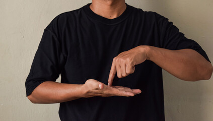 Young man with nude manicure keeping forefinger on raised palm on sign language