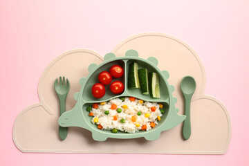 Healthy kids meal on dinosaur plate with fresh vegetables and rice. Baby food serving concept.