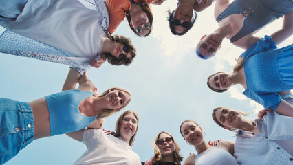 Group of recent graduates forming a circle, linking arms, and waving