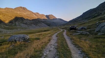 Obraz premium Scenic mountain landscape with a dirt path surrounded by rocky terrain and lush grass.