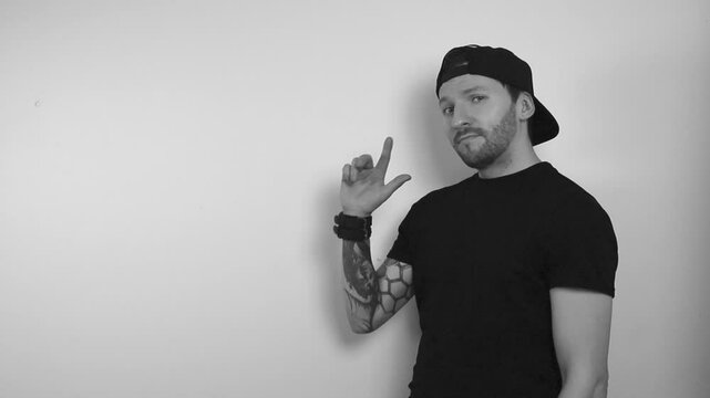 Grayscale footage of a tattooed man thinking about something that he agrees with by nodding and points into the empty upper left corner with his finger and continues to nod and be happy.