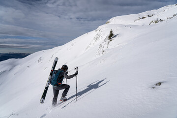 skier in the mountains, hiking and carrying skis in the snow. French alps, savoie